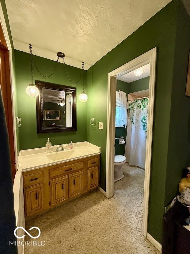 full bath featuring toilet, vanity, and baseboards