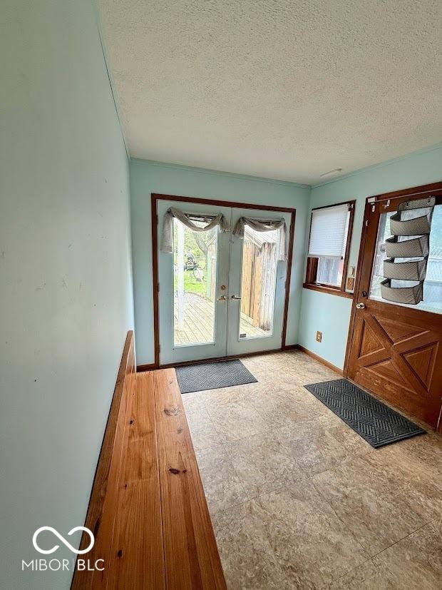 doorway to outside featuring french doors, a textured ceiling, and baseboards