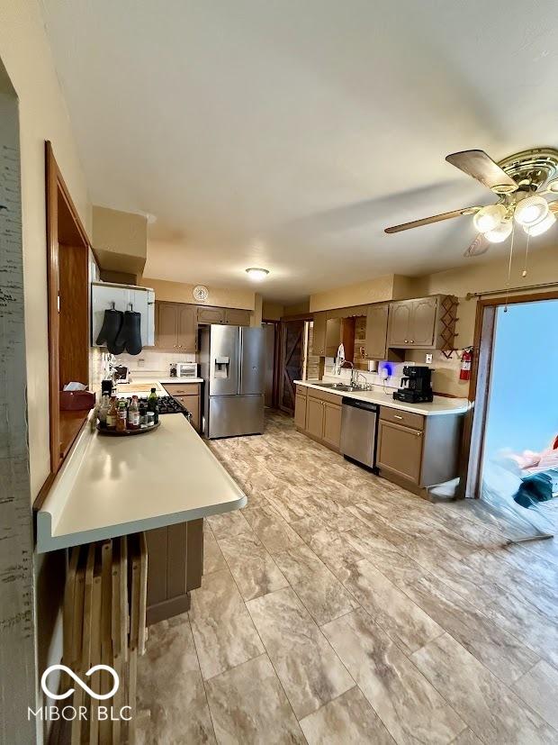 kitchen with stainless steel appliances, light countertops, and a ceiling fan