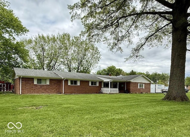 rear view of house with brick siding and a yard
