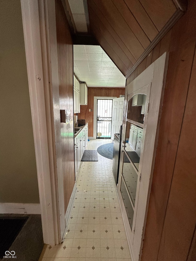 803 W 12th St, Anderson, IN 46016 - kitchen featuring wood walls, light floors, baseboards, and wall chimney exhaust hood