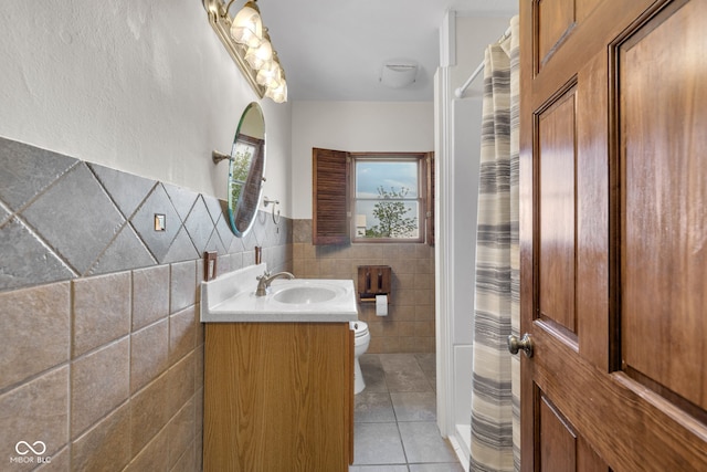 bathroom with tile walls, tile patterned floors, toilet, vanity, and a shower with shower curtain