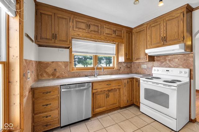 kitchen with white electric range, stainless steel dishwasher, a sink, under cabinet range hood, and brown cabinets