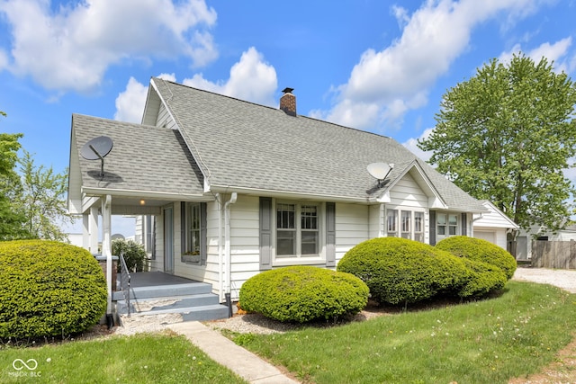 view of front of home with covered porch, a chimney, and a shingled roof