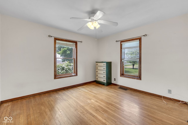 spare room featuring light wood finished floors, baseboards, and ceiling fan