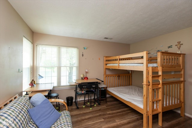 bedroom featuring wood finished floors, baseboards, and a textured ceiling