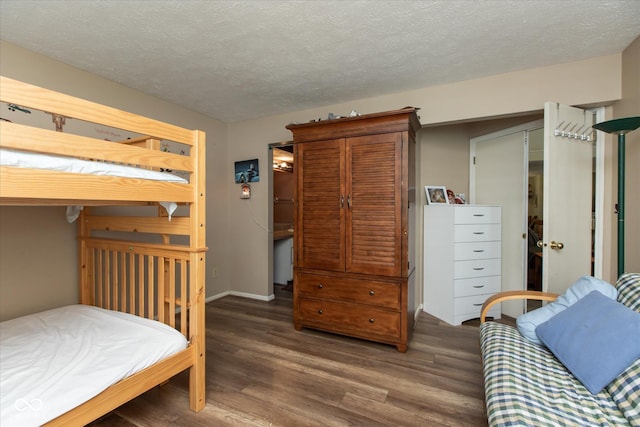 bedroom featuring wood finished floors, a textured ceiling, and baseboards