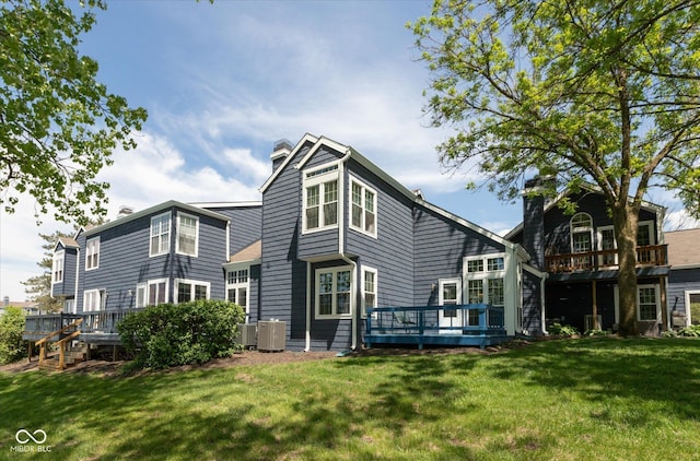 back of property featuring a chimney, a deck, central AC, and a yard