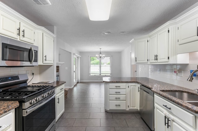 kitchen with appliances with stainless steel finishes, a sink, a textured ceiling, white cabinetry, and tasteful backsplash