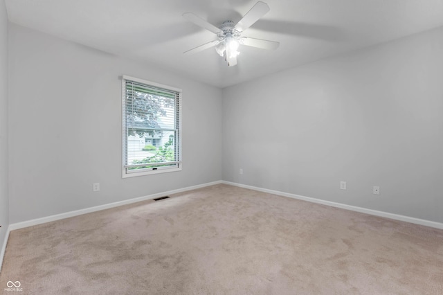 empty room with carpet floors, a ceiling fan, and baseboards