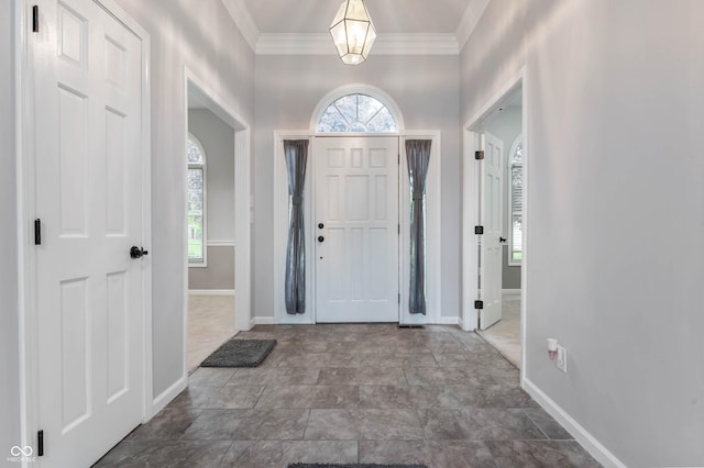 foyer featuring plenty of natural light, baseboards, and crown molding
