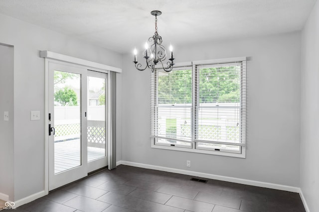 unfurnished dining area with healthy amount of natural light, baseboards, and a chandelier