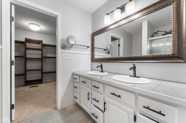 full bathroom featuring tile patterned floors, double vanity, and a shower
