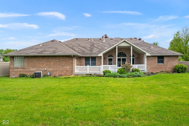 back of house featuring brick siding, central air condition unit, a lawn, and a shingled roof
