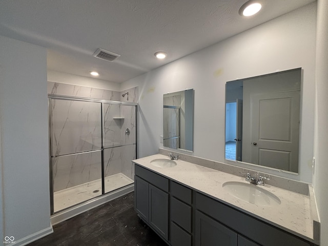 bathroom featuring a marble finish shower, double vanity, wood finished floors, and recessed lighting