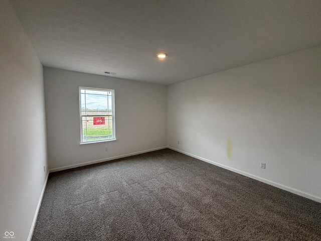 unfurnished room with dark colored carpet and baseboards