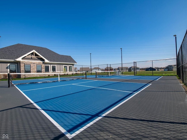 view of tennis court featuring community basketball court and fence