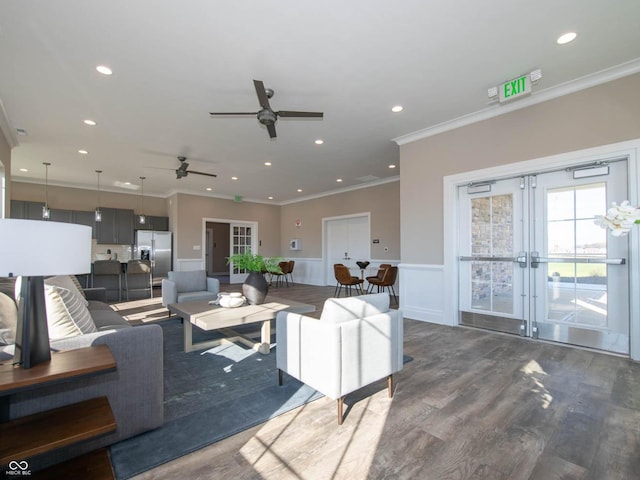 living area featuring french doors, ceiling fan, wainscoting, crown molding, and dark wood finished floors