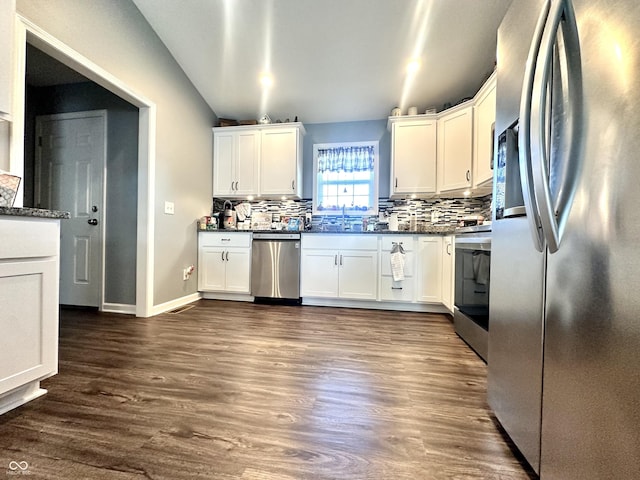 kitchen with stainless steel appliances, backsplash, white cabinetry, dark countertops, and dark wood-style floors