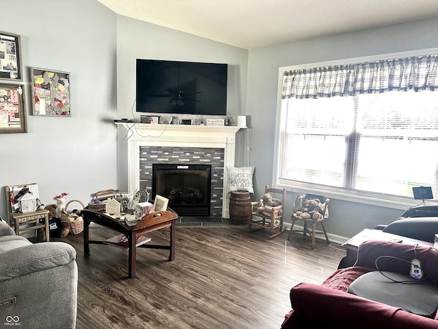 living room with vaulted ceiling, wood finished floors, a tiled fireplace, and baseboards