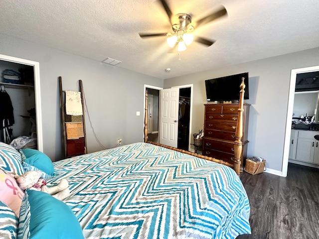 bedroom with dark wood-style flooring, a spacious closet, a closet, and a textured ceiling
