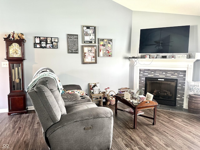 living area featuring lofted ceiling, wood finished floors, a fireplace, ceiling fan, and baseboards