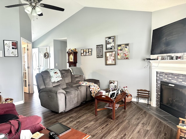 living area with a fireplace, vaulted ceiling, wood finished floors, ceiling fan, and baseboards
