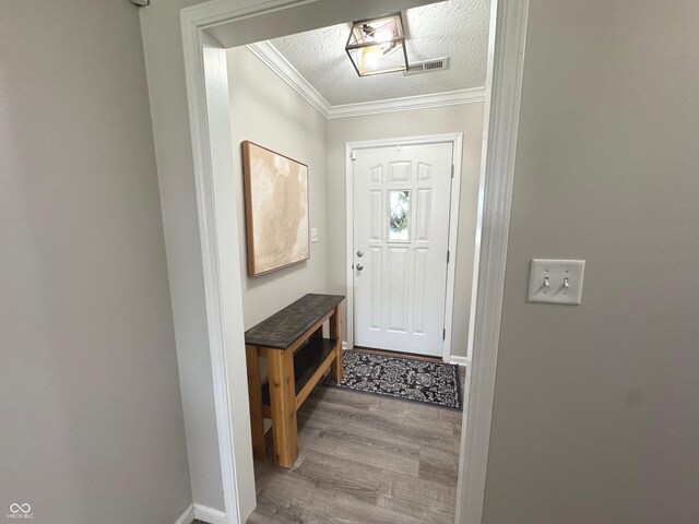 entryway with wood finished floors, ornamental molding, baseboards, and a textured ceiling