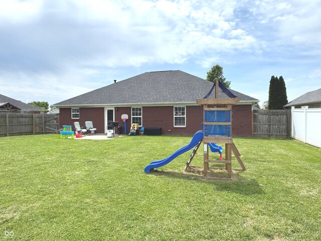 rear view of house with brick siding, a playground, and roof with shingles