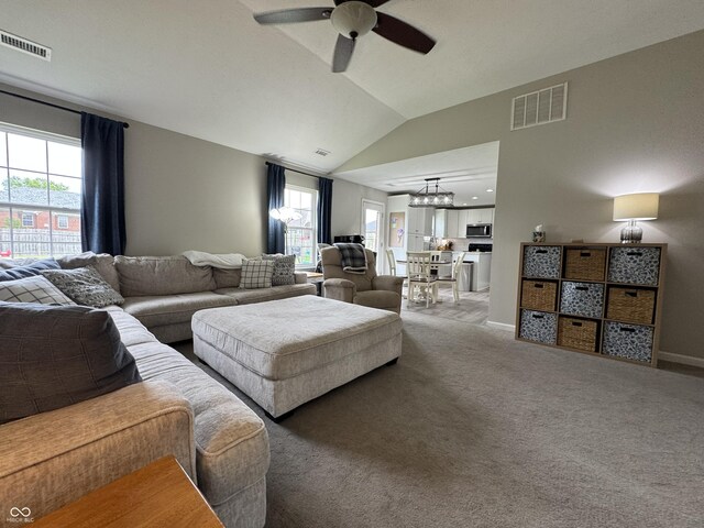 living room with ceiling fan, vaulted ceiling, plenty of natural light, light colored carpet, and baseboards