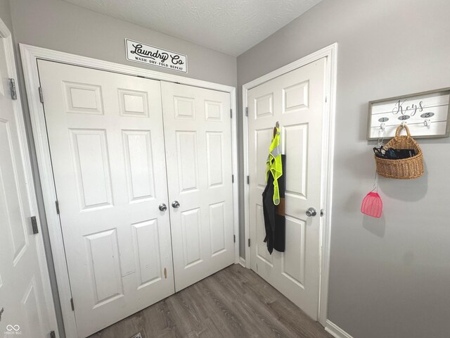 mudroom with dark wood-type flooring, a textured ceiling, and baseboards
