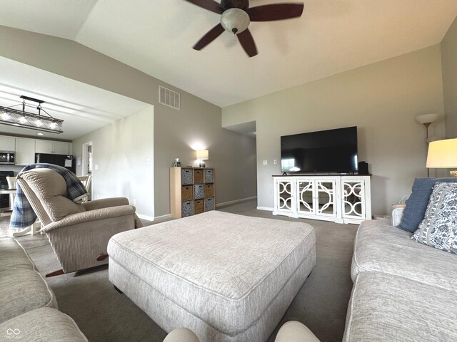 living area with a ceiling fan, dark colored carpet, vaulted ceiling, and baseboards