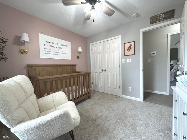 carpeted bedroom featuring a closet, baseboards, ceiling fan, and a textured ceiling
