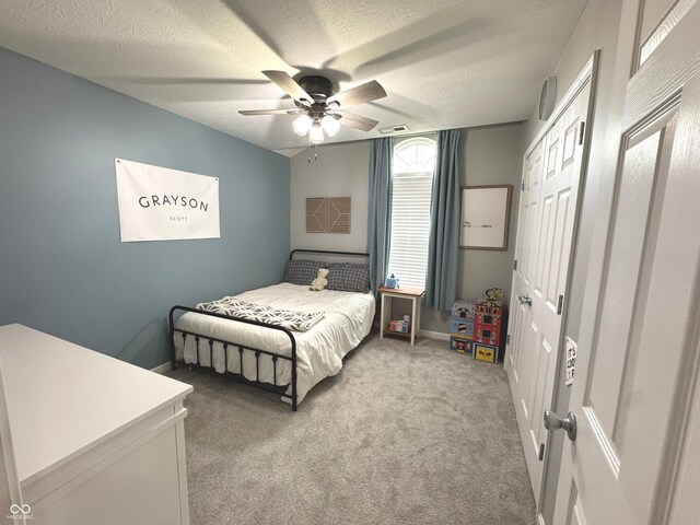 bedroom with light colored carpet, ceiling fan, and a textured ceiling