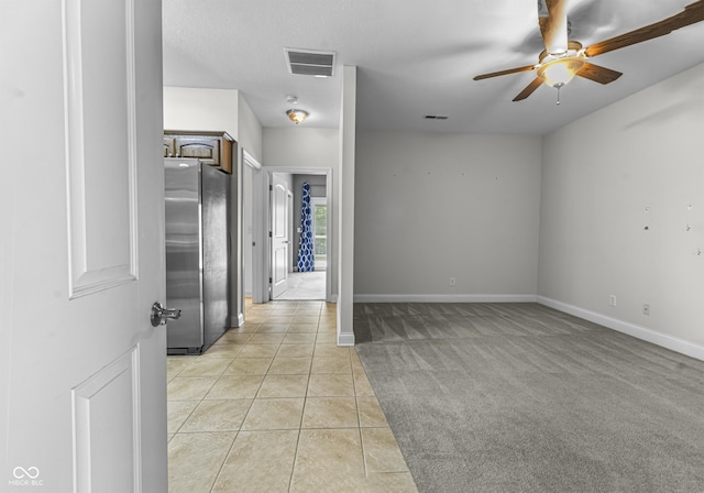 unfurnished room with a ceiling fan, light tile patterned floors, baseboards, and light carpet