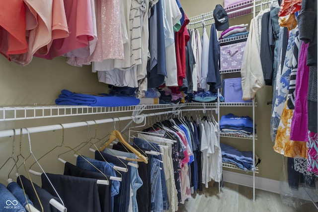 walk in closet with wood finished floors