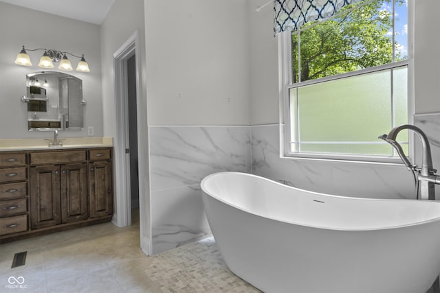 bathroom with vanity, tile walls, a freestanding tub, a wainscoted wall, and tile patterned flooring