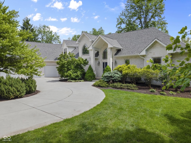 view of front facade with a shingled roof, a front lawn, brick siding, concrete driveway, and a garage
