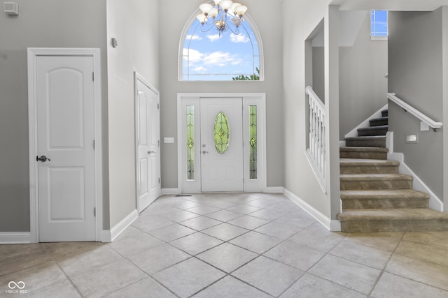 foyer featuring a high ceiling, light tile patterned floors, a chandelier, plenty of natural light, and stairs