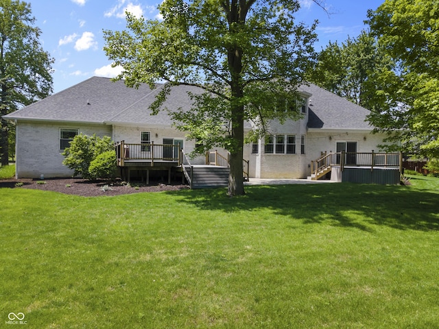rear view of property with a wooden deck, a yard, roof with shingles, and brick siding