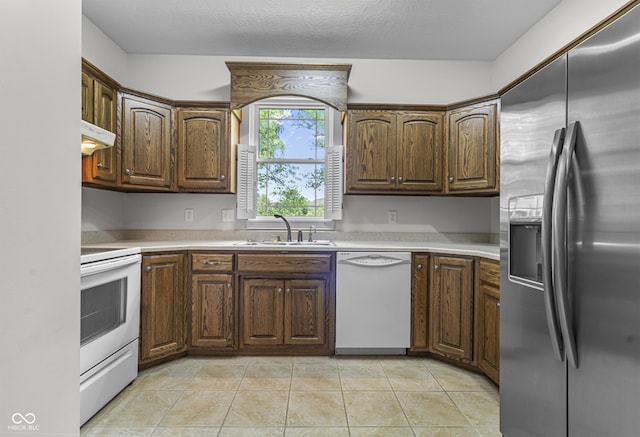 kitchen with white appliances, under cabinet range hood, a sink, light countertops, and light tile patterned flooring