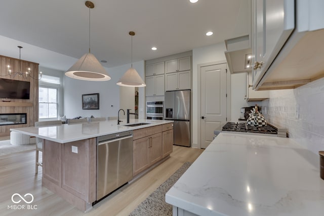 17346 Newton Main St, Westfield, IN 46074 - kitchen featuring stainless steel appliances, a sink, light wood-type flooring, backsplash, and a center island with sink