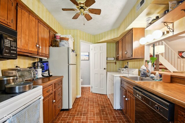 kitchen with black appliances, a sink, washing machine and clothes dryer, brick patterned floors, and ceiling fan