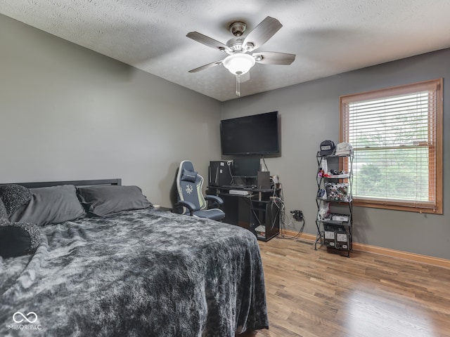 bedroom featuring wood finished floors, baseboards, ceiling fan, and a textured ceiling