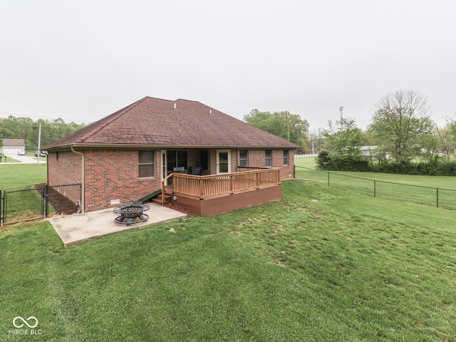 rear view of property featuring a fire pit, a wooden deck, brick siding, a patio, and a gate