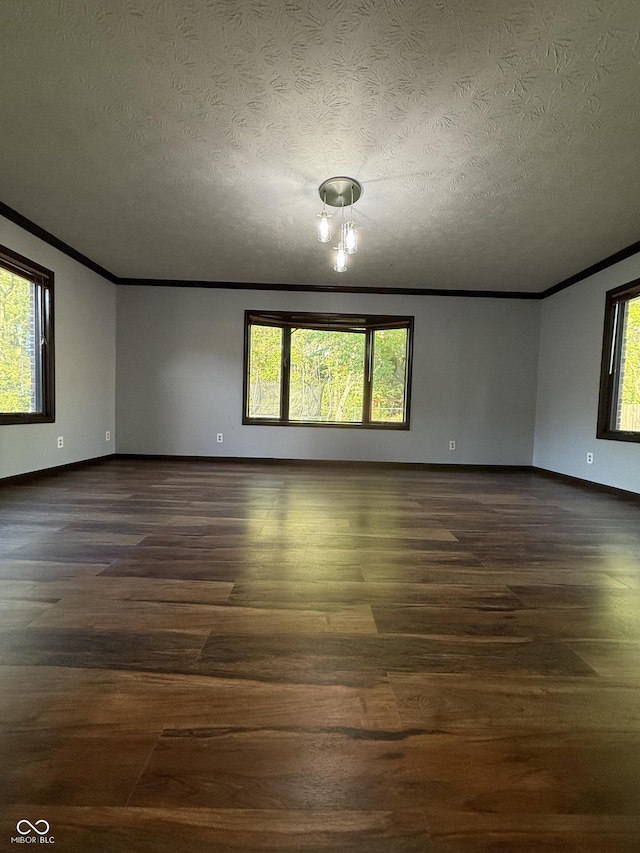 empty room with crown molding, baseboards, dark wood-style flooring, and a textured ceiling