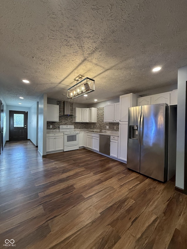 kitchen featuring appliances with stainless steel finishes, a sink, wall chimney exhaust hood, a textured ceiling, and dark wood-style floors