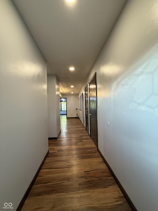 hallway with dark wood-style floors, recessed lighting, and baseboards