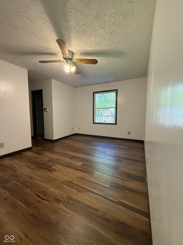 empty room with baseboards, dark wood-type flooring, ceiling fan, and a textured ceiling
