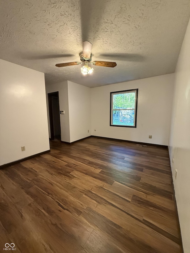 empty room featuring dark wood-type flooring, baseboards, ceiling fan, and a textured ceiling